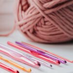 Skill Set - Closeup of row of multicolored crochet needles and ball of beige threads for knitting in bright room