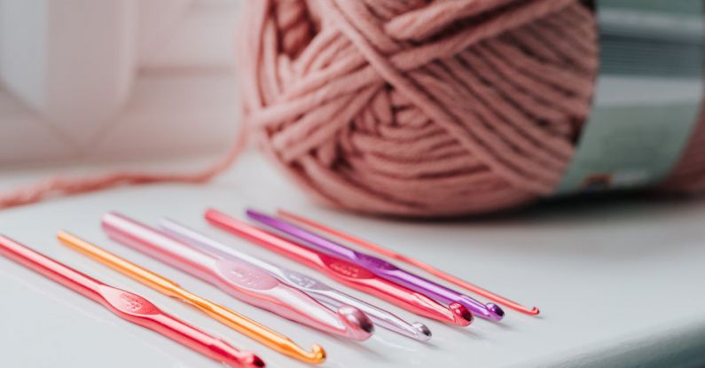 Skill Set - Closeup of row of multicolored crochet needles and ball of beige threads for knitting in bright room