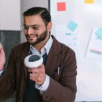 Investment Pitch - Man in Brown Coat Holding White and Gray Game Controllers