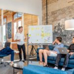 KPIs - three men sitting while using laptops and watching man beside whiteboard