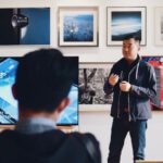 Mentors - Man Beside Flat Screen Television With Photos Background